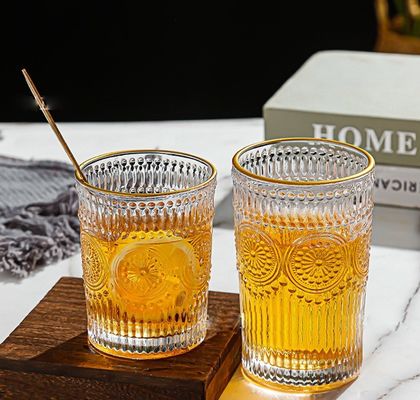 Une tasse en verre à bord en or avec un design en tournesol et un style classique.