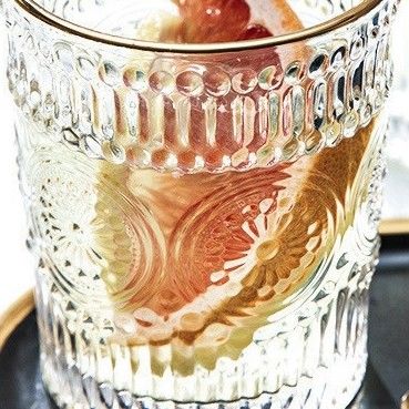 Une tasse en verre à bord en or avec un design en tournesol et un style classique.